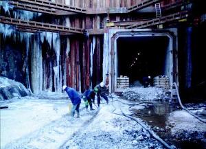 FOTO - Ústí tunelu pod Vltavou, pod řekou je již možno přejít suchou nohou. Ze staveniště v Troji to mají dělníci Metrostavu do Holešovic již jen 170 metrů.